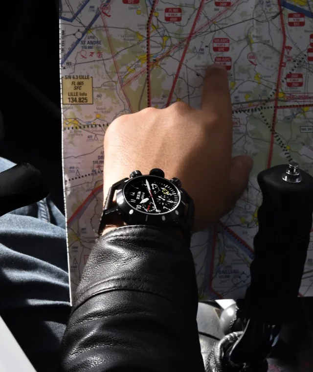 Chronographe Aéro au poignet d'un pilote, sur une carte de navigation