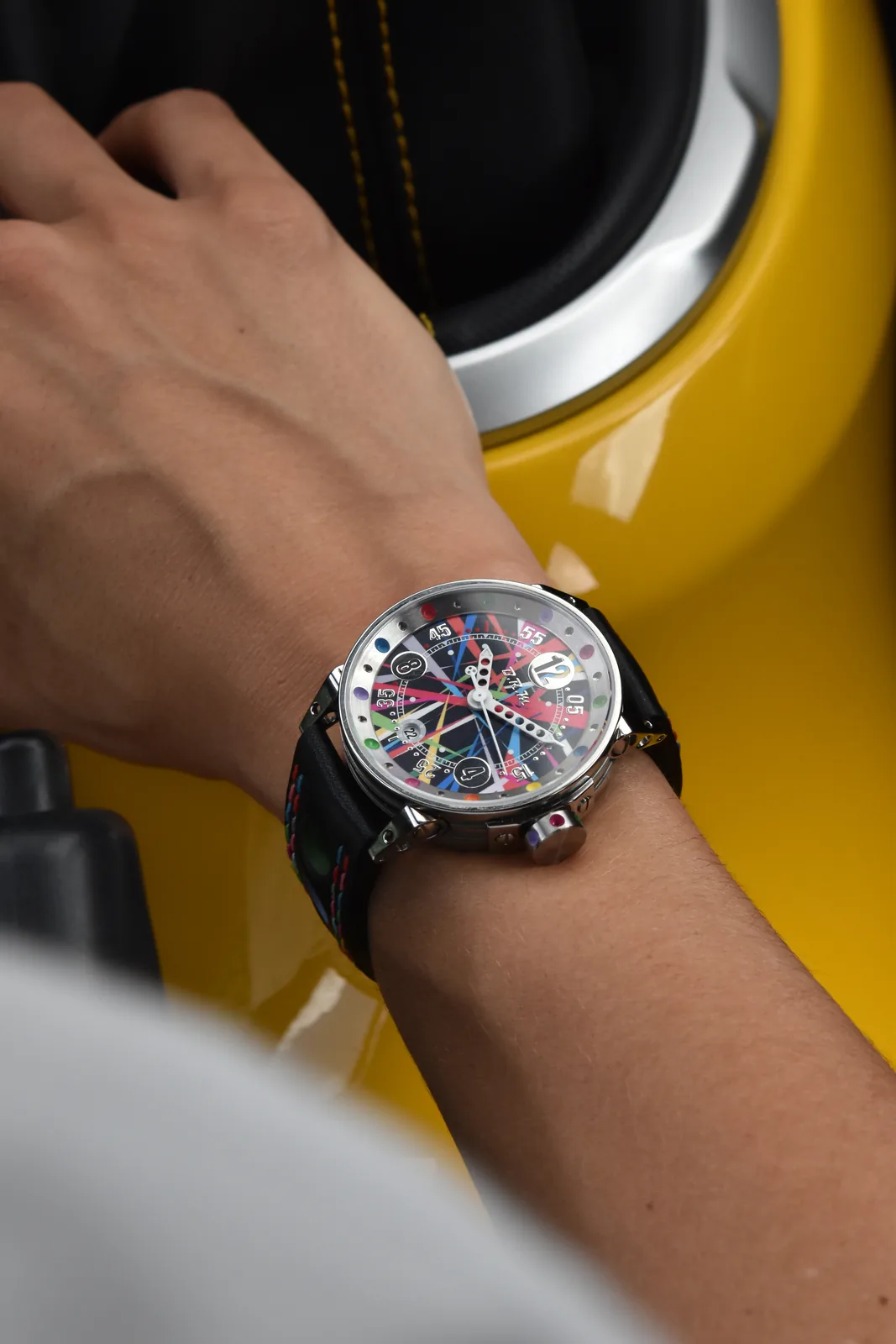 Montre Art Car au poignet, contre la carrosserie jaune d'une voiture