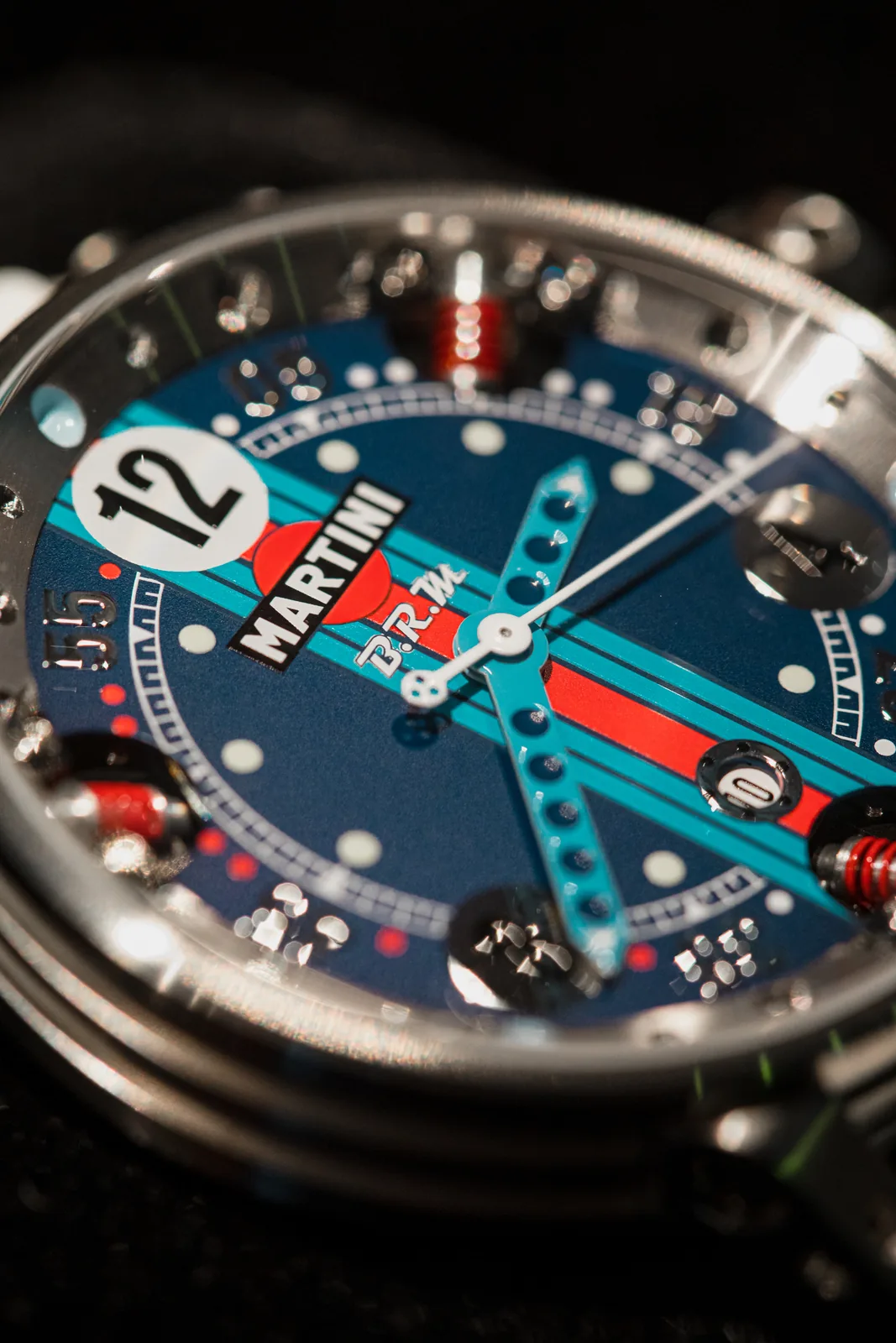 Blaues Zifferblatt in Martini Racing Lackierung in Großaufnahme: hellblaue und rote Bänder, Ziffer 12 in ihrer weißen Pastille, himmelblau durchbrochene Zeiger