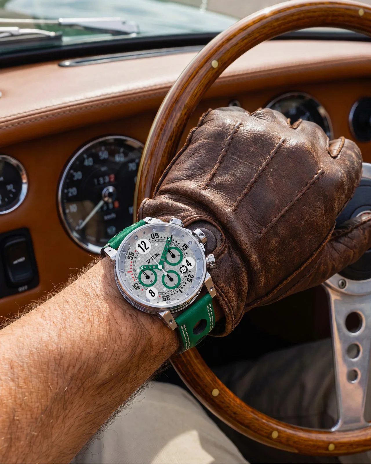 V12-44 Grün British am Handgelenk, behandschuhte Hand am Holzlenkrad